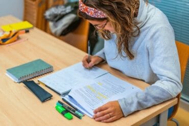 Student revising with notes, mind maps, and past papers for long-form exam preparation